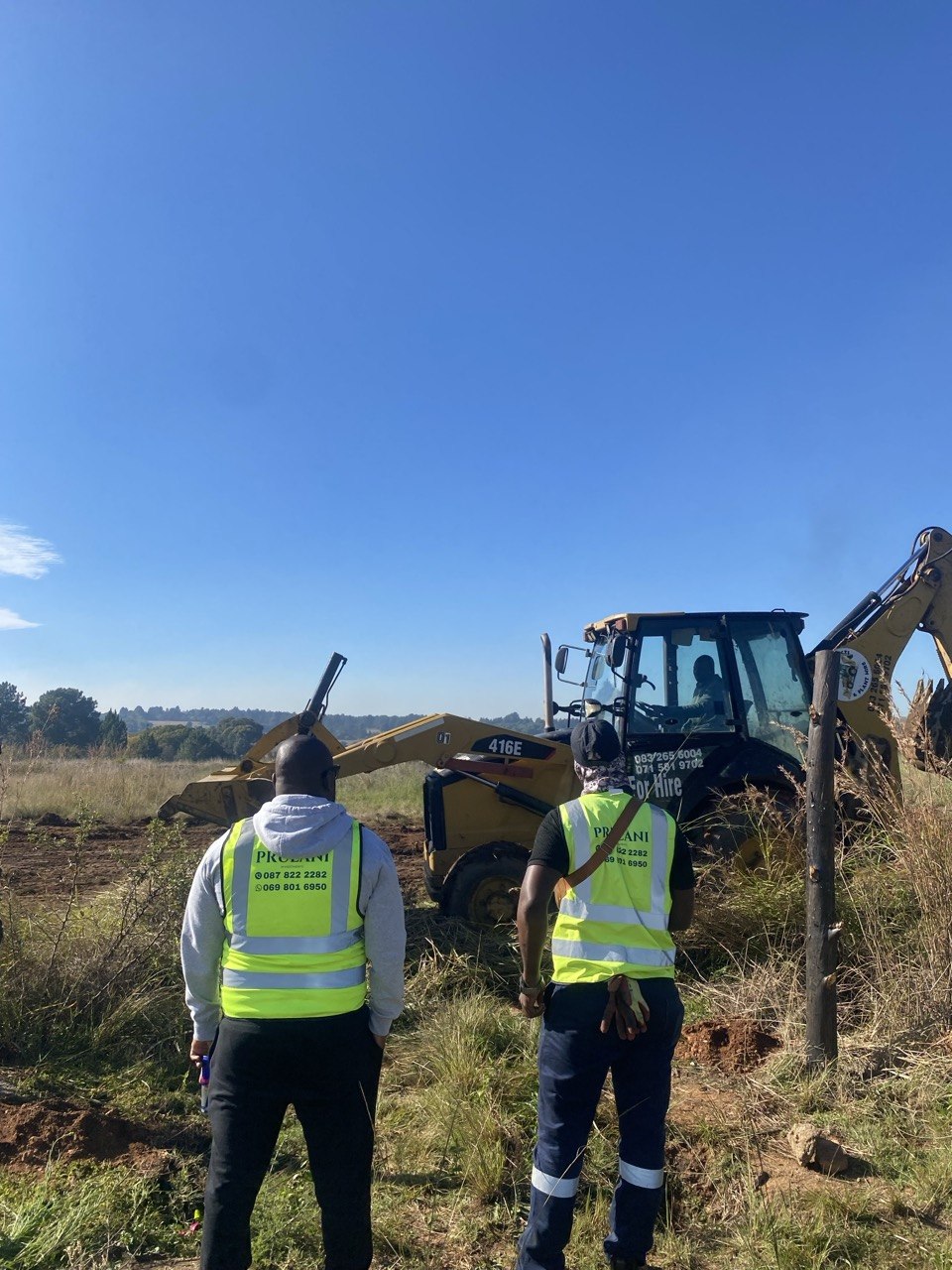 Prulani team watching TLB/backhoe site clearing at Cosmo Peak